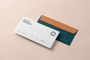 Full surface envelopes, one white with sample branding and one teal with an orange flap, on a peach background