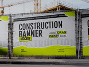 Construction banners with a lime green and grey sample design on site fencing, with a crane and building site behind
