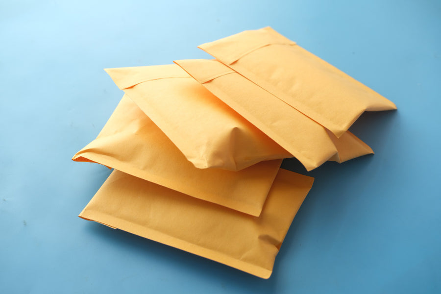 Pile of yellow kraft-style padded envelopes on a pale blue surface