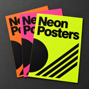 Three neon posters in fluorescent orange, pink and yellow with bold black sample designs on a dark surface