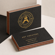 Black multi layer business cards with orange striped edges and a gold Art Creators logo on cream