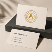 Two cream classic business cards with a gold Art Creators logo on the front and sample contact details