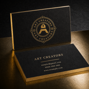 Black deluxe business cards with a gold Art Creators logo and sample contact details on a dark gold surface